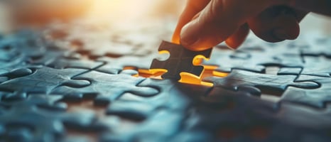 Close-up of hand placing puzzle piece, highlighting warning signs in mergers & acquisitions | vcfo Blog