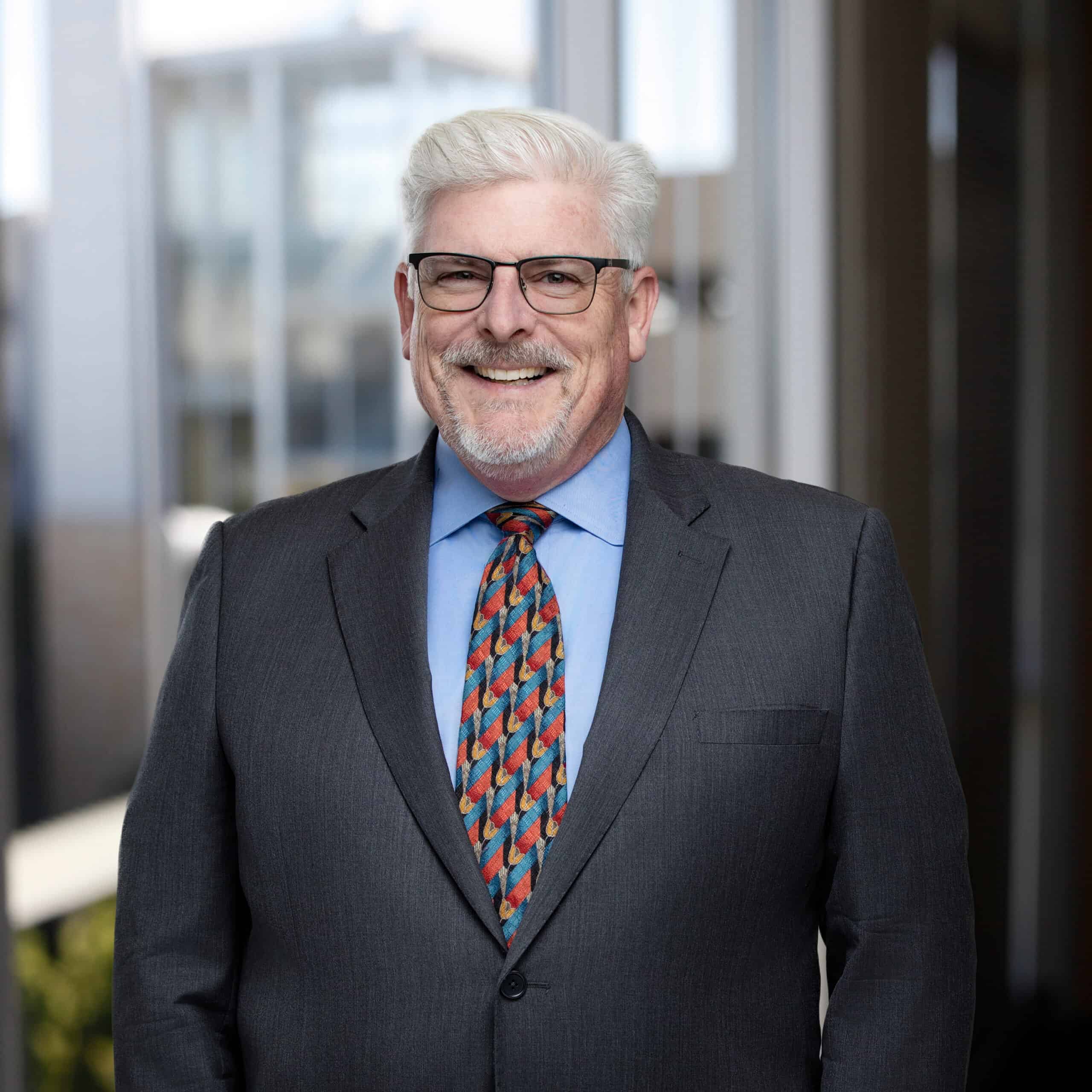 Portrait of Alan Docherty, vcfo executive, in business suit at office.