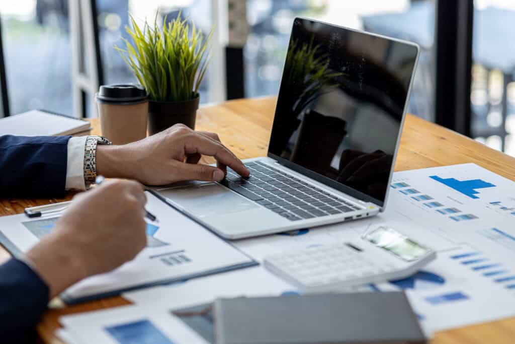 Business professional analyzing financial reports on a laptop during a strategic meeting.