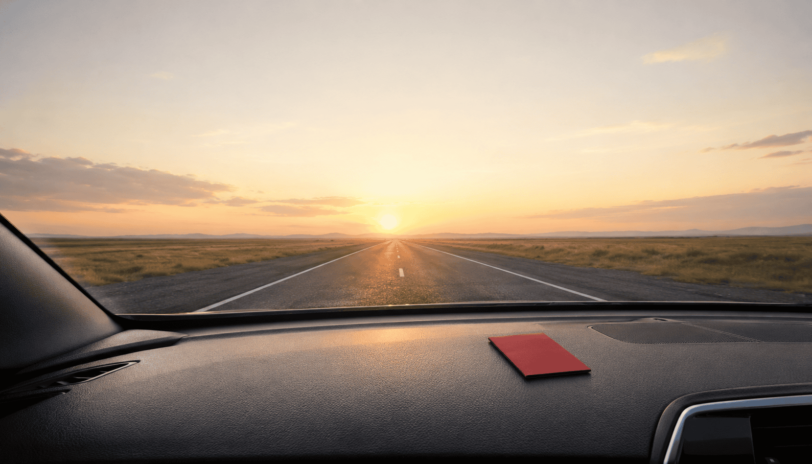 Sunset view from inside a car on an open road, symbolizing journey and direction.
