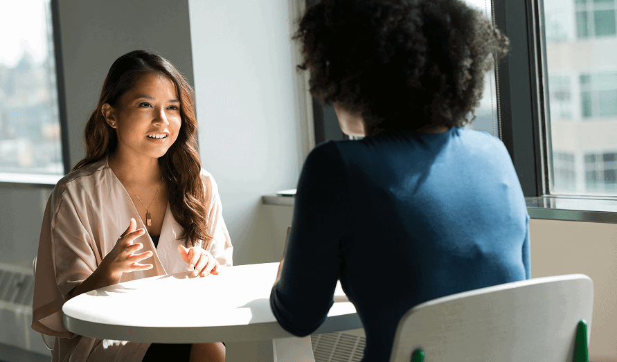 Two women having a professional discussion in an office setting.