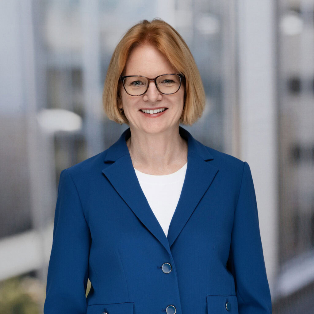 Businesswoman wearing glasses and blue blazer in modern office setting.
