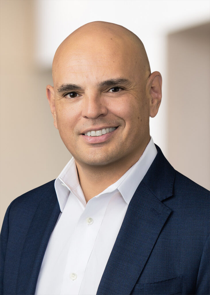 Professional businessman in a navy suit smiling for the camera.