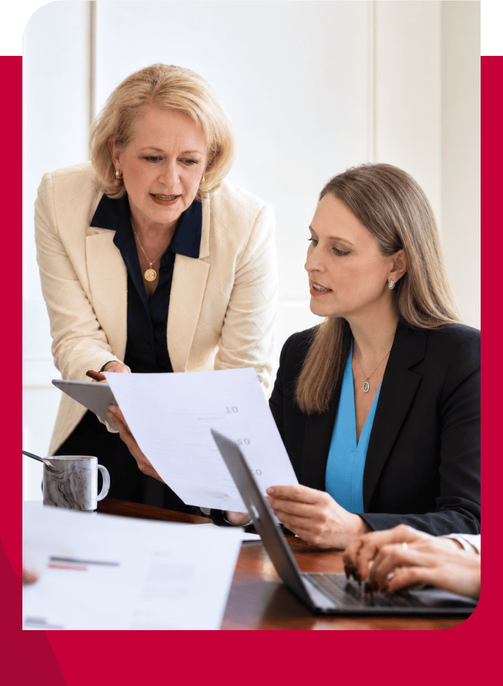 Two professional women discussing documents in a business meeting.