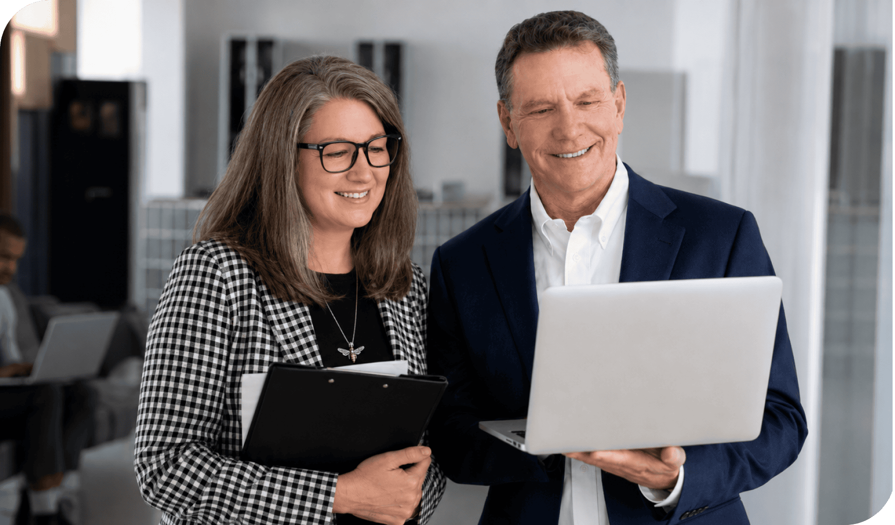 Business professionals discussing data on a laptop in an office setting.