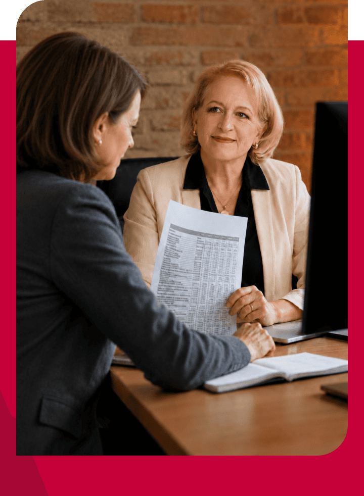 Two women in a professional meeting discussing financial documents.