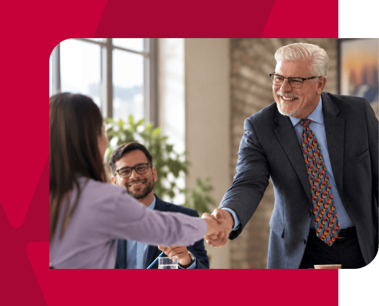 Business handshake between a senior man and a woman in a professional setting.