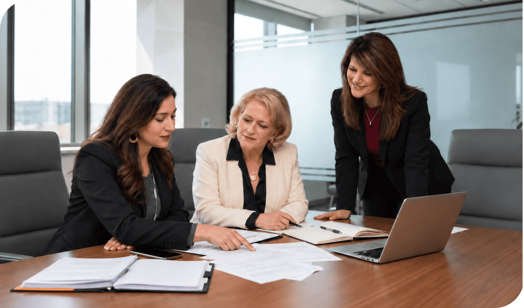 Businesswomen discussing HR strategies in a modern office conference room.