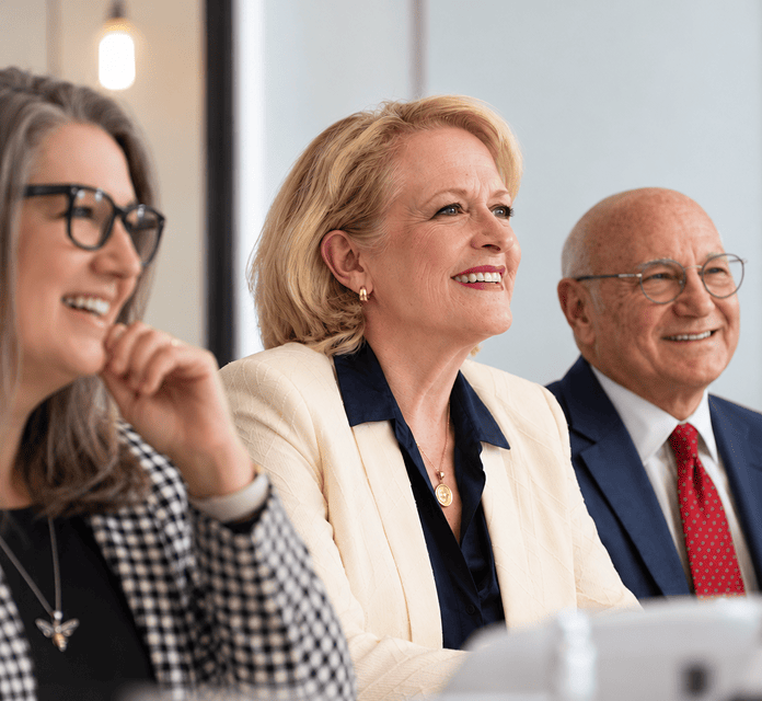Business professionals smiling during a meeting or conference.