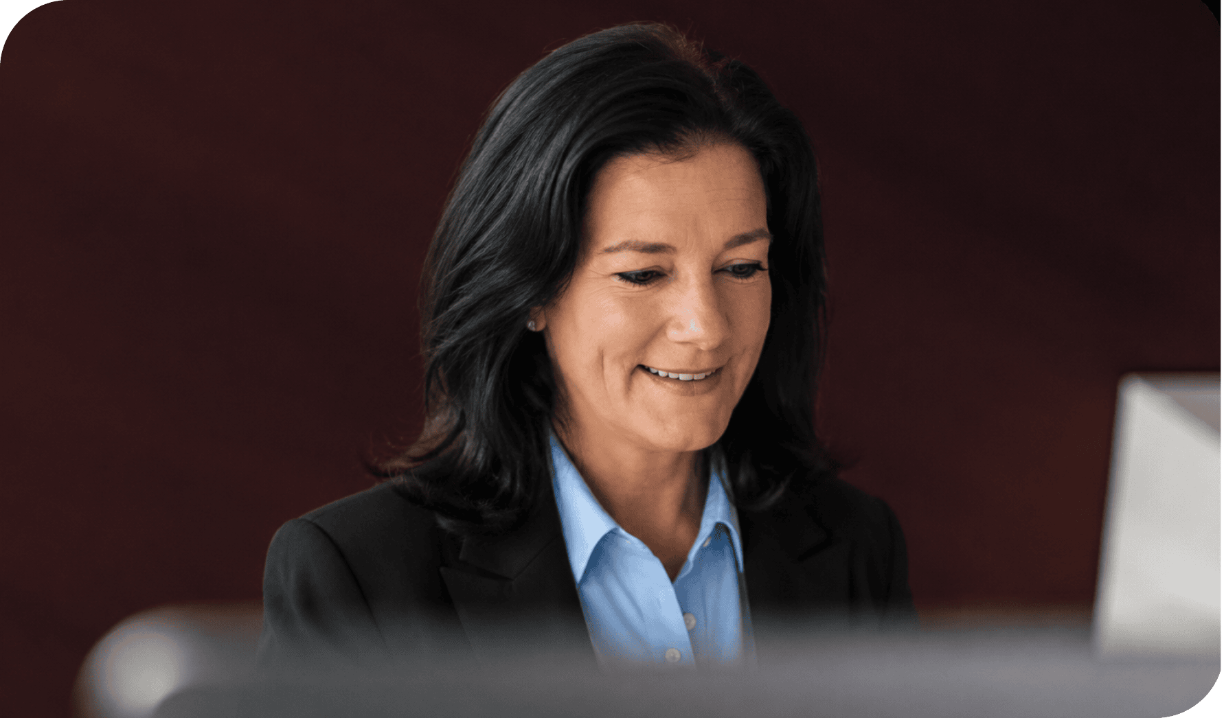 Businesswoman smiling while working at her desk in an office setting.